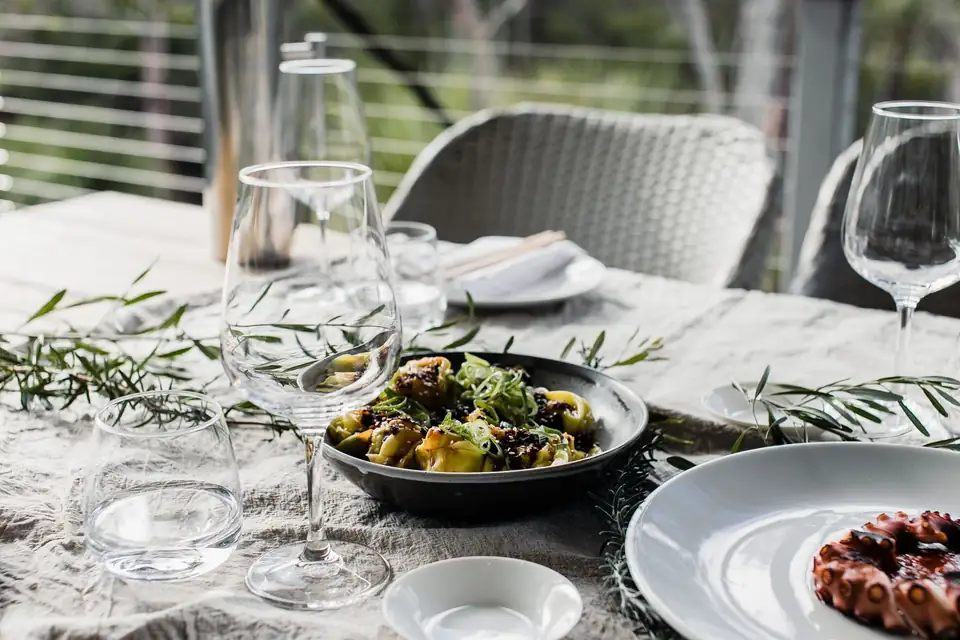 Plates of food on an outdoor table, with grilled seafood and salad.